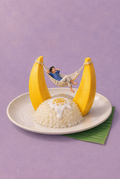 Gezeichnete Miniaturperson in einer Hängematte zwischen zwei Mangostücken über einem Teller Mango Sticky Rice auf lilafarbenem Grund